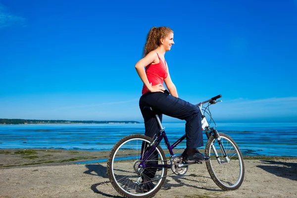 Schöne Frau mit Fahrrad am Meer — Stockfoto