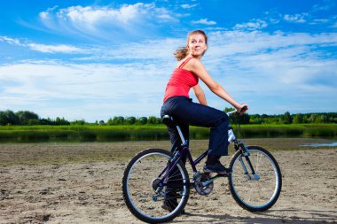 Beautiful woman with bicycle at the sea clipart