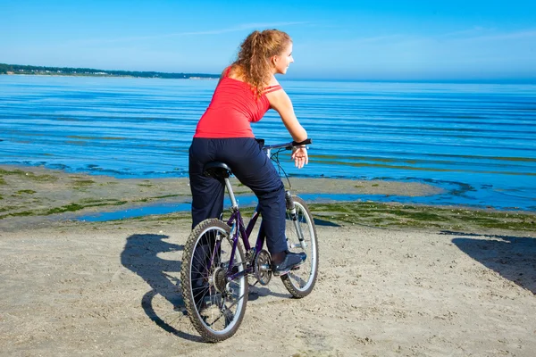 Belle femme avec vélo à la mer — Photo