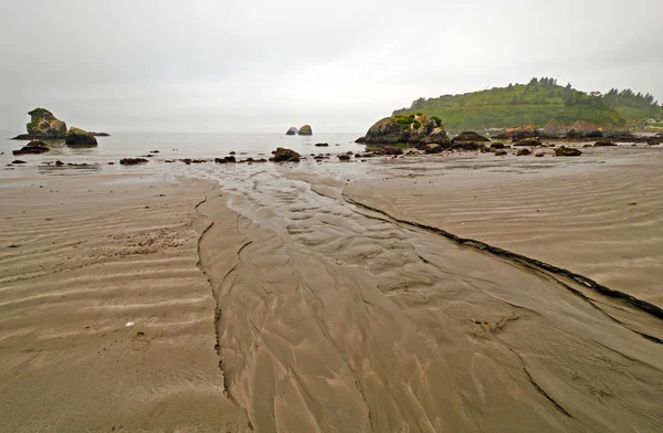 Agua dulce corriendo hacia el océano en una playa de arena — Foto de Stock