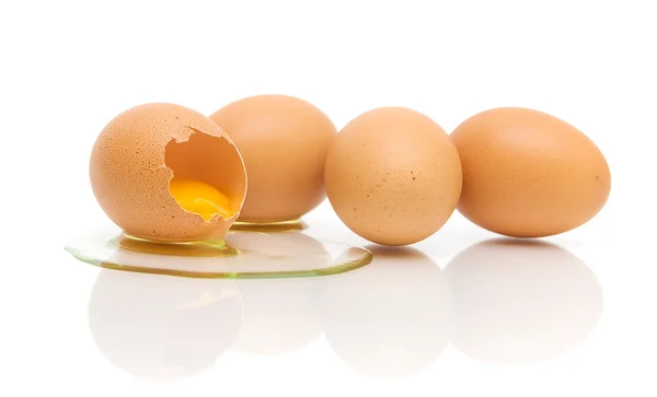 Ein gebrochenes und drei ganze Eier auf weißem Hintergrund — Stockfoto