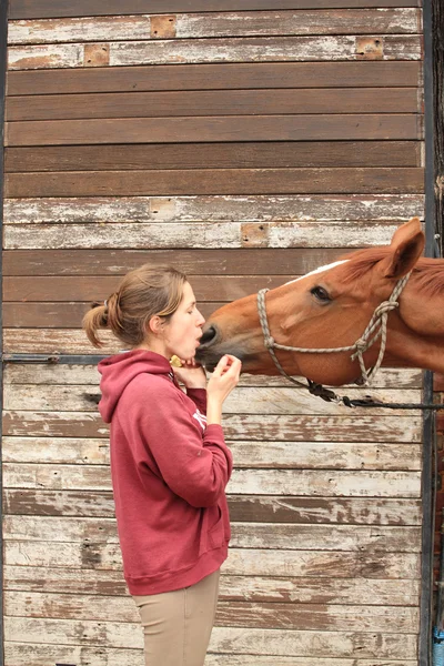 Mooie vrouwen geven een appel aan haar paard — Stockfoto
