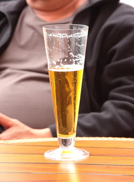 stock image Glass of beer with a background the belly of a man