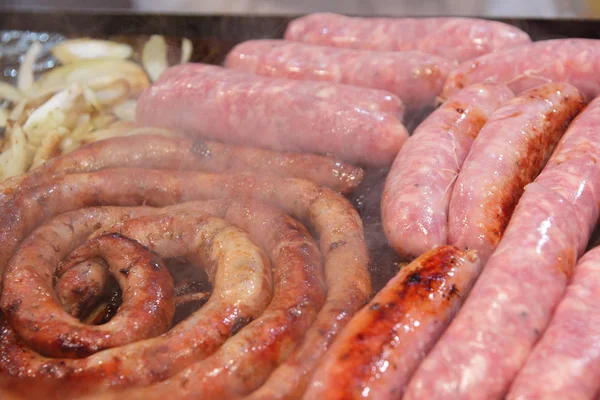 stock image Cooking different varieties of sausages with onions