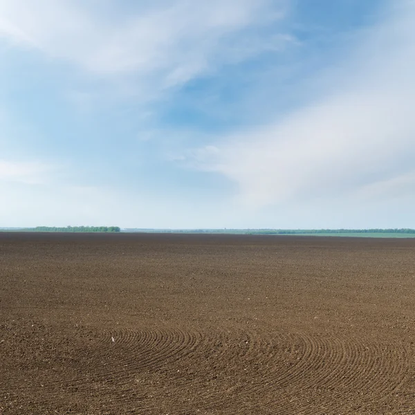 Black ploughed field in spring under cloudy sky — Stock Photo, Image