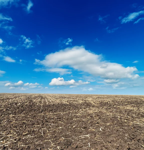 Campo cultivado negro y cielo azul — Foto de Stock