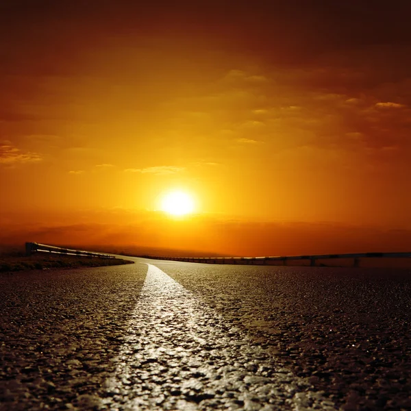 Асфальтированная дорога в красный закат — стоковое фото