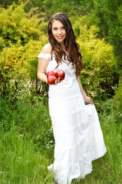 Портрет счастливой молодой женщины с красными яблоками на природе, на открытом воздухе — стоковое фото