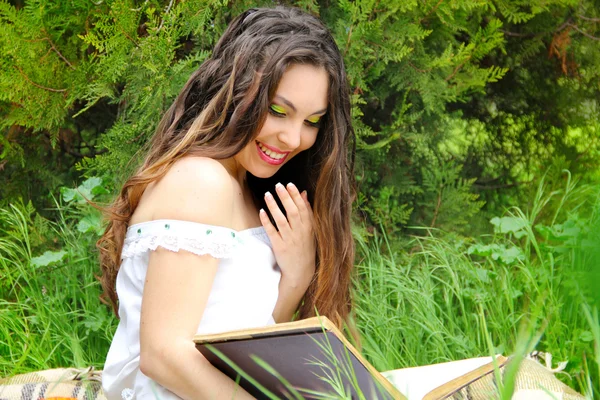 Щаслива усміхнена молода жінка читає книгу, зовнішній портрет — стокове фото