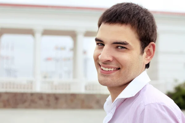 Крупный план Портрет счастливого улыбающегося человека над архитектурным зданием на открытом воздухе — стоковое фото