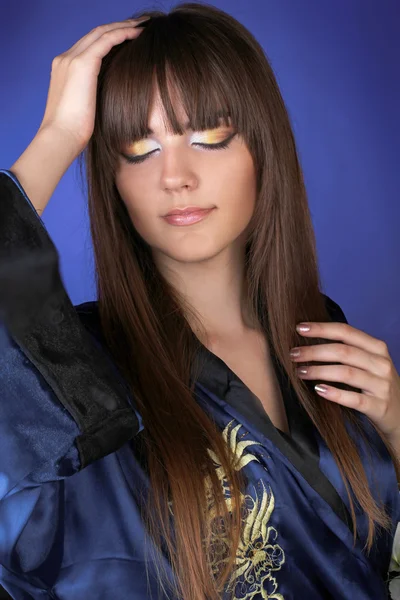 Poserar Sensuell kvinna med långt hår och make up, över blå — Stockfoto