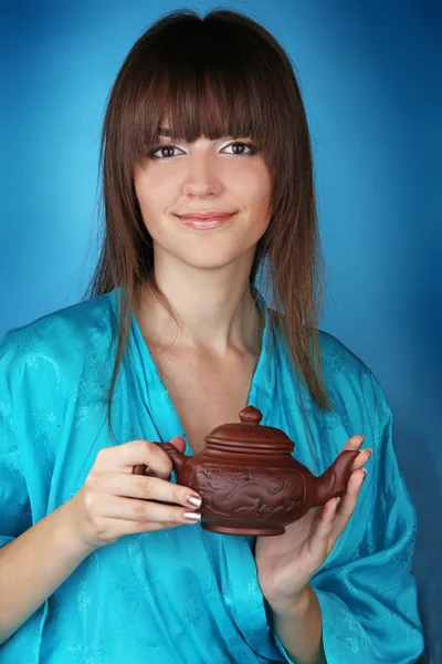 Teezeremonie mit schöner junger Frau auf blauem Hintergrund Stockbild