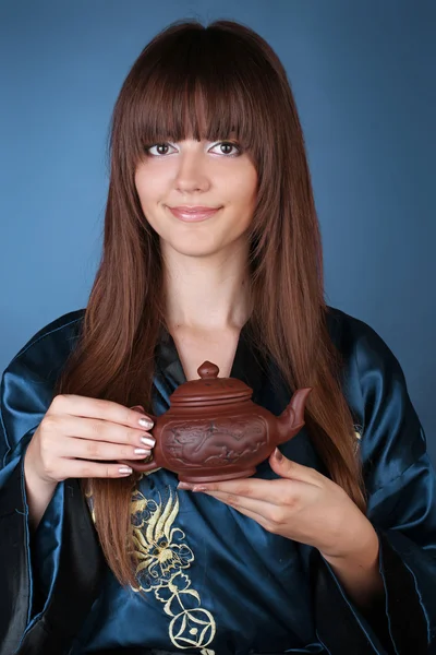 Cérémonie du thé femme aux longs cheveux bruns, théière sur les mains sur bl Photos De Stock Libres De Droits