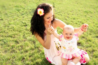 Happy mother with daughter relaxing sitting on grass clipart