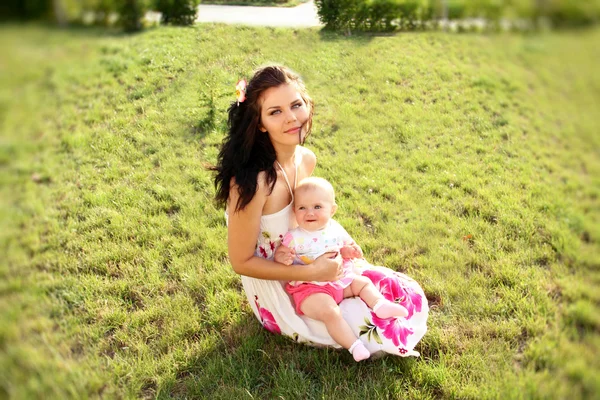 Madre con bambino seduto al campo verde all'aperto — Foto Stock