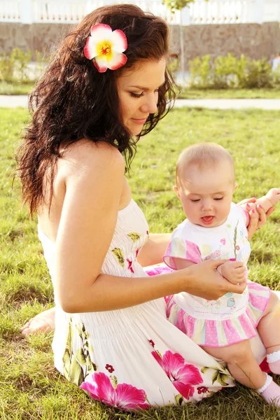 Beautiful young mother daughter relaxing sitting on green grass — Stock Photo, Image