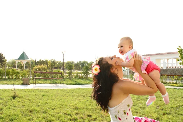 Mamma anläggning söt baby, över parken utomhus — Stockfoto