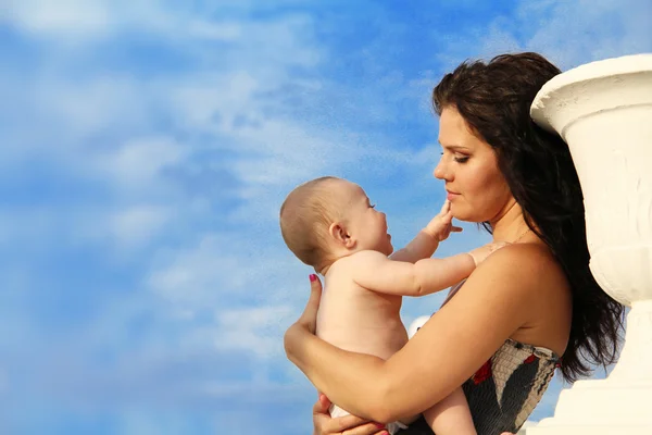 Hermosa madre con bebé sobre el cielo azul — Foto de Stock