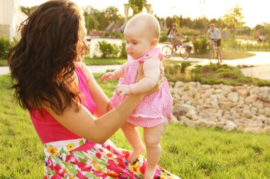 Baby making first steps with mother help clipart