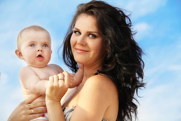 Happy mother with funny lovely baby over blue sky — Stock Photo, Image