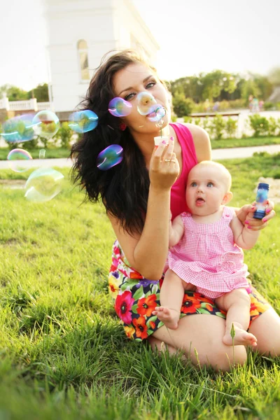 Mother blowing bubbles with funny baby — Stock Photo, Image