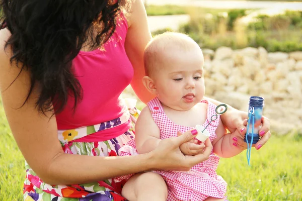 Baby blowing bubbles with mother help — Stock Photo, Image