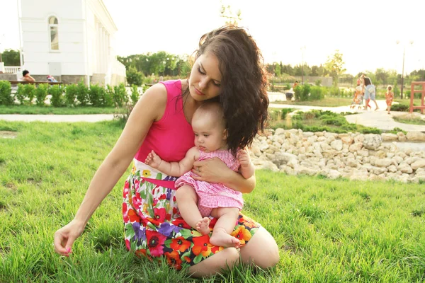 緑のスプリング フィールドで彼女の赤ちゃんとリラックスの母 — ストック写真