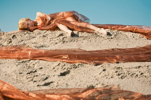 Girl lying on sand in orange cloth — Stock Photo, Image