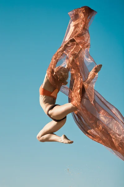 Девушка танцует с большой оранжевой тканью — стоковое фото