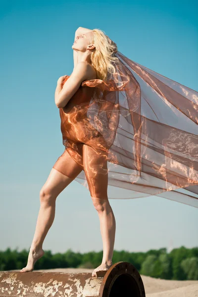 Девушка танцует с большой оранжевой тканью — стоковое фото