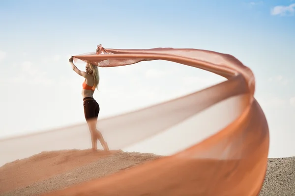 Mädchen tanzen mit großem orangefarbenem Tuch — Stockfoto