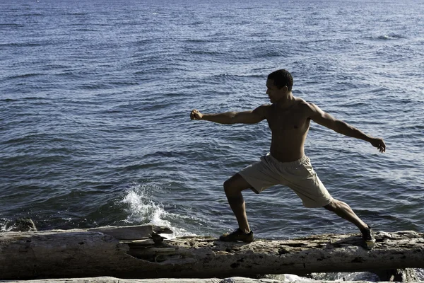 Yoga på stranden med ung svart man — Stockfoto