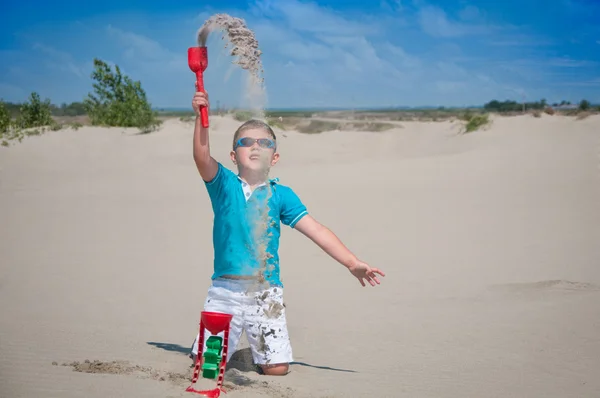 Aranyos kisfiú játszik a homokos tengerparton — Stock Fotó
