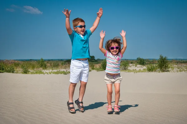 Entzückende kleine Mädchen und Jungen spielen am Sandstrand — Stockfoto