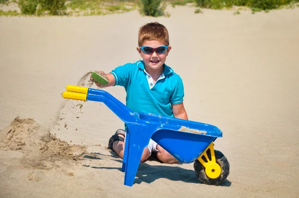 Adorable little boy playing on the sandy beach — Zdjęcie stockowe
