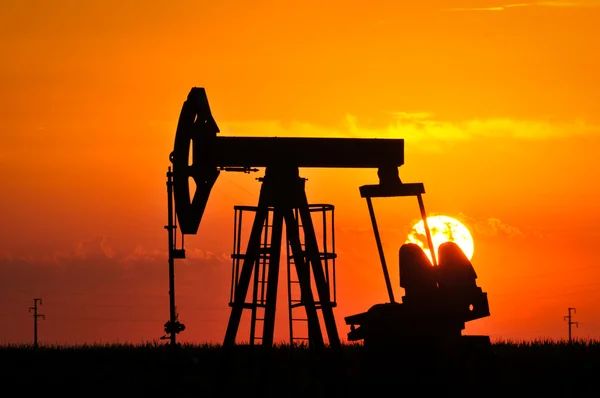 石油泵杰克倒映的落山的太阳 — 图库照片