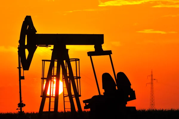 En olja pump jack är silhuett av solen — Stockfoto