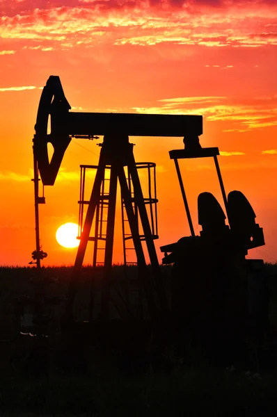 Uma tomada de bomba de óleo é silhueta pelo pôr-do-sol — Fotografia de Stock