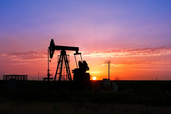 Uma tomada de bomba de óleo é silhueta pelo pôr-do-sol — Fotografia de Stock