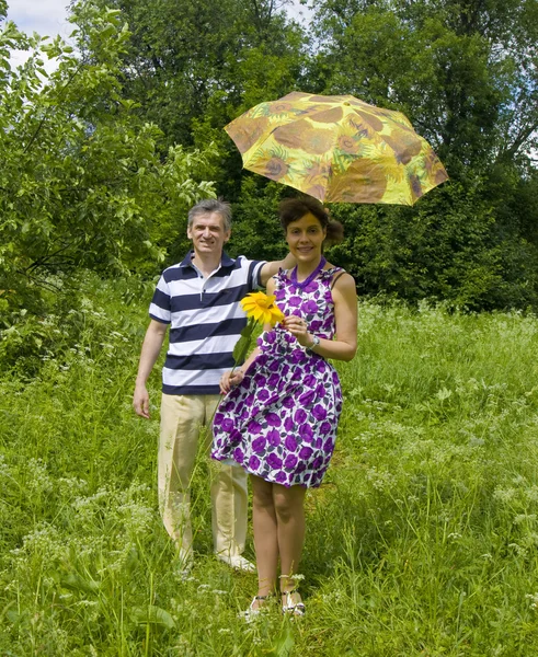 Młody mężczyzna i kobieta ze słonecznika i żółty parasol — Zdjęcie stockowe