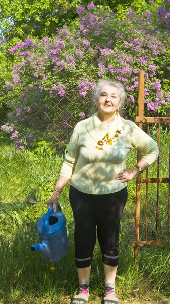 Old lady with watering can in garden — Stock Photo, Image