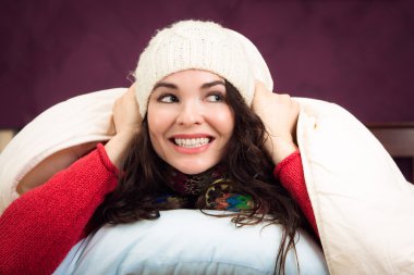 Happy woman peeking out from under blankets clipart