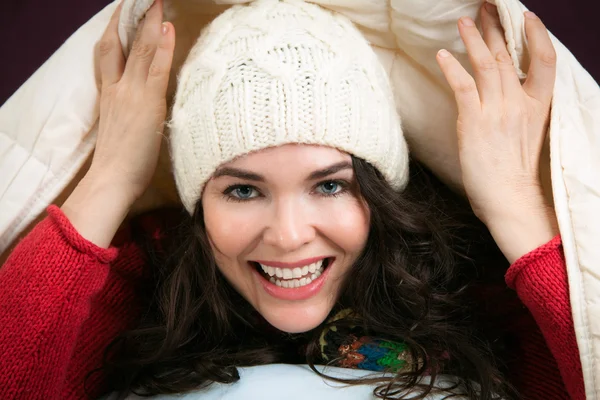 stock image Happy woman peeking out from under blankets