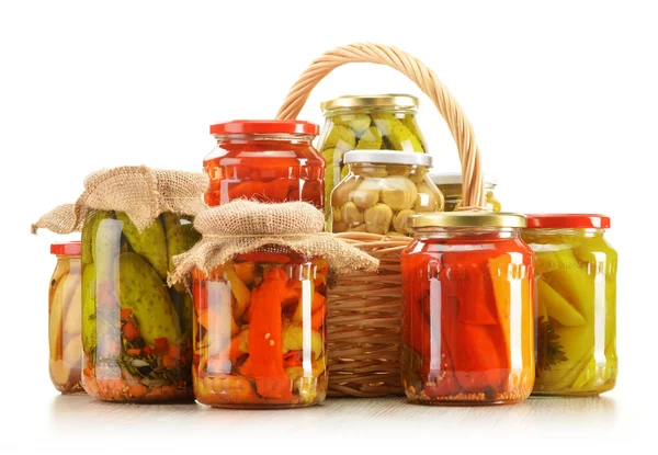 Composition with wicker basket and jars of pickled vegetables. — Stock Photo, Image