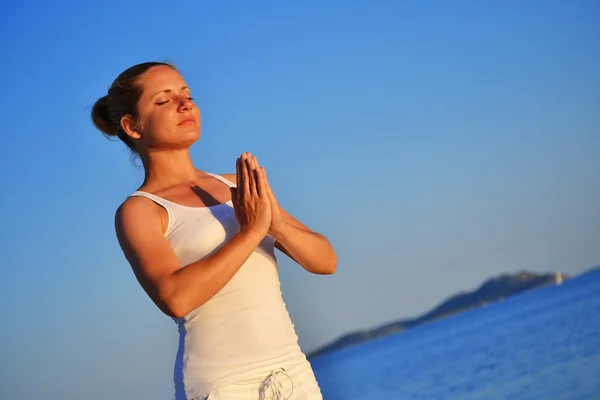 Молодая женщина во время йоги медитации на пляже — стоковое фото