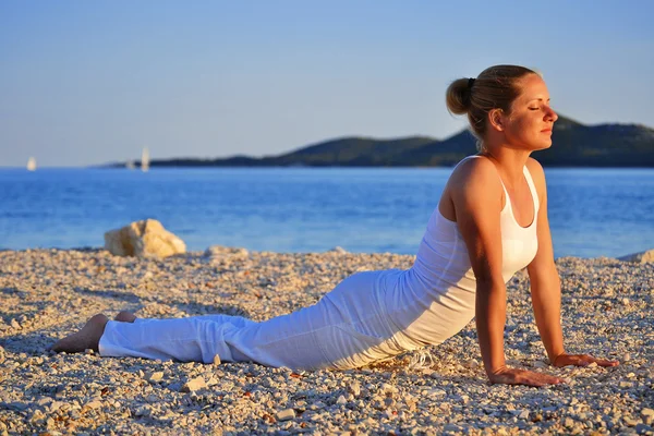 Jonge vrouw tijdens yoga meditatie op het strand — Stockfoto
