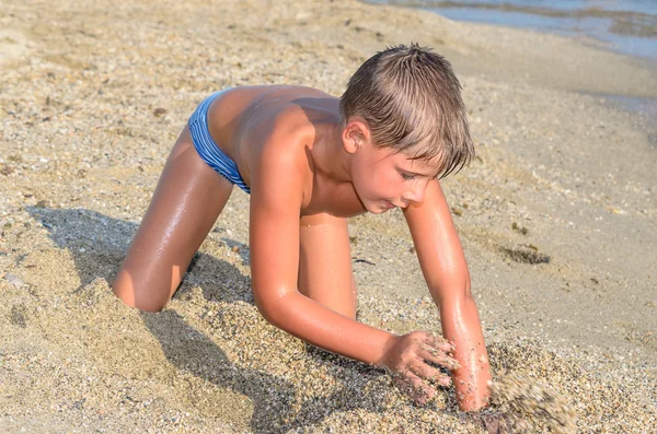 Junge spielt im Sand am Strand — Stockfoto