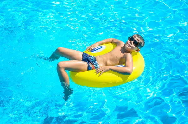 Мальчик плавает по надувному кругу в бассейне . — стоковое фото