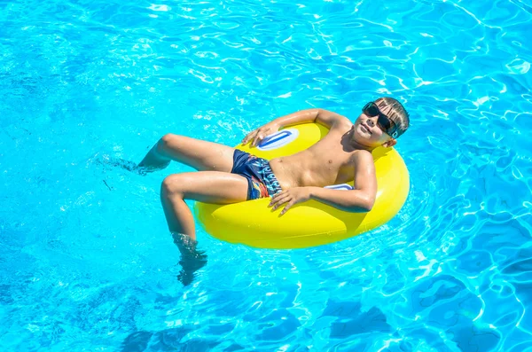Pojke som flyter på en uppblåsbar cirkel i poolen. Royaltyfria Stockfoton