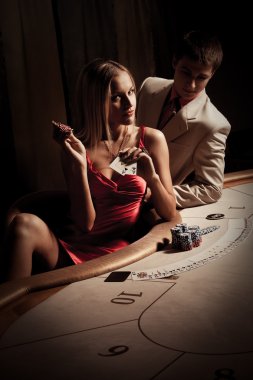 Young man & woman playing poker in casino clipart